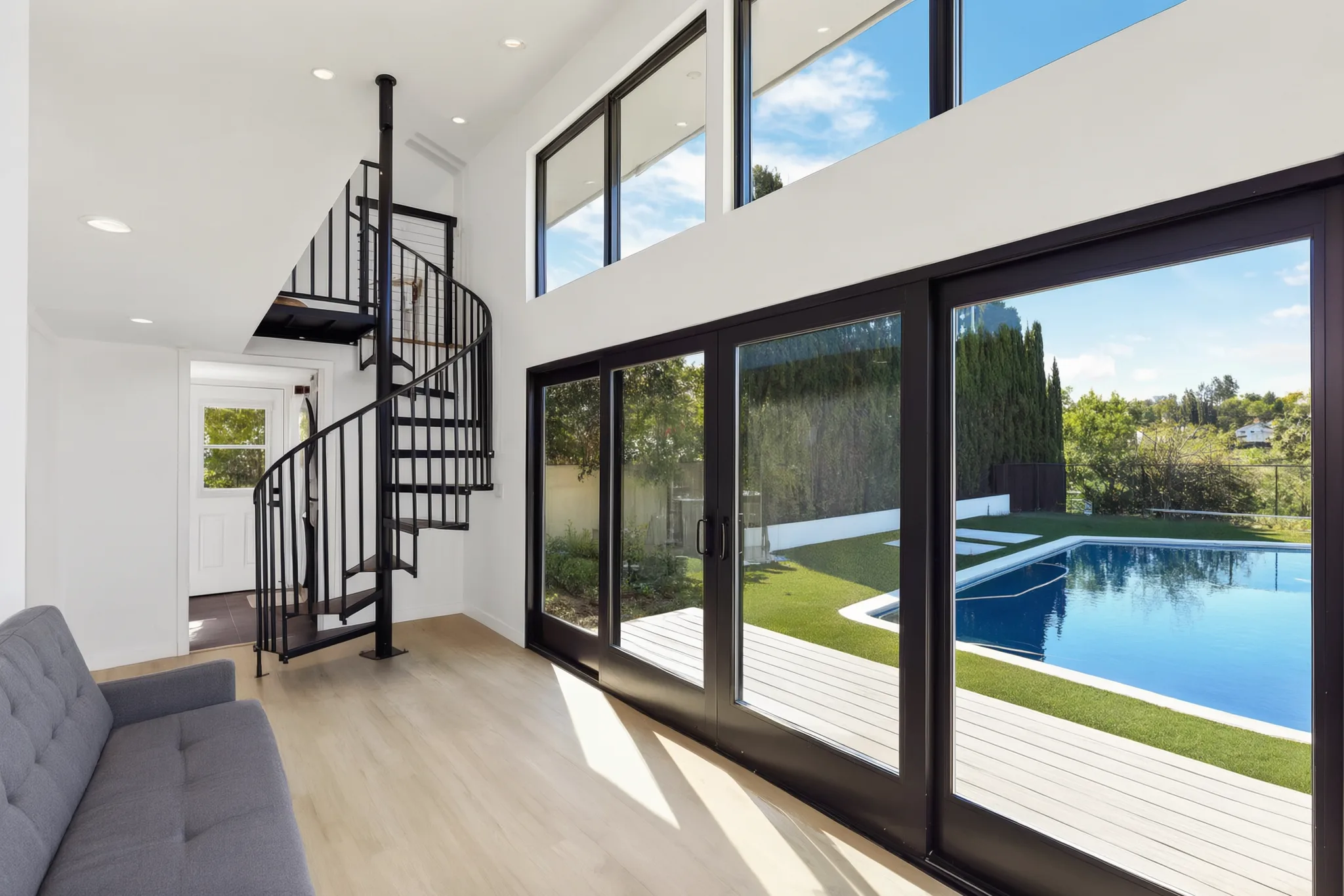 A double-height room with floor-to-ceiling glass onto a pool and yard, in a modern Avorino build in Orange County